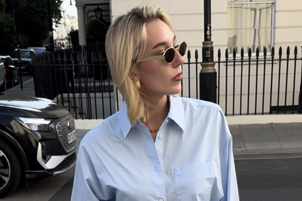 A lady with blonde hair, wearing sunglasses and a blue shirt.
